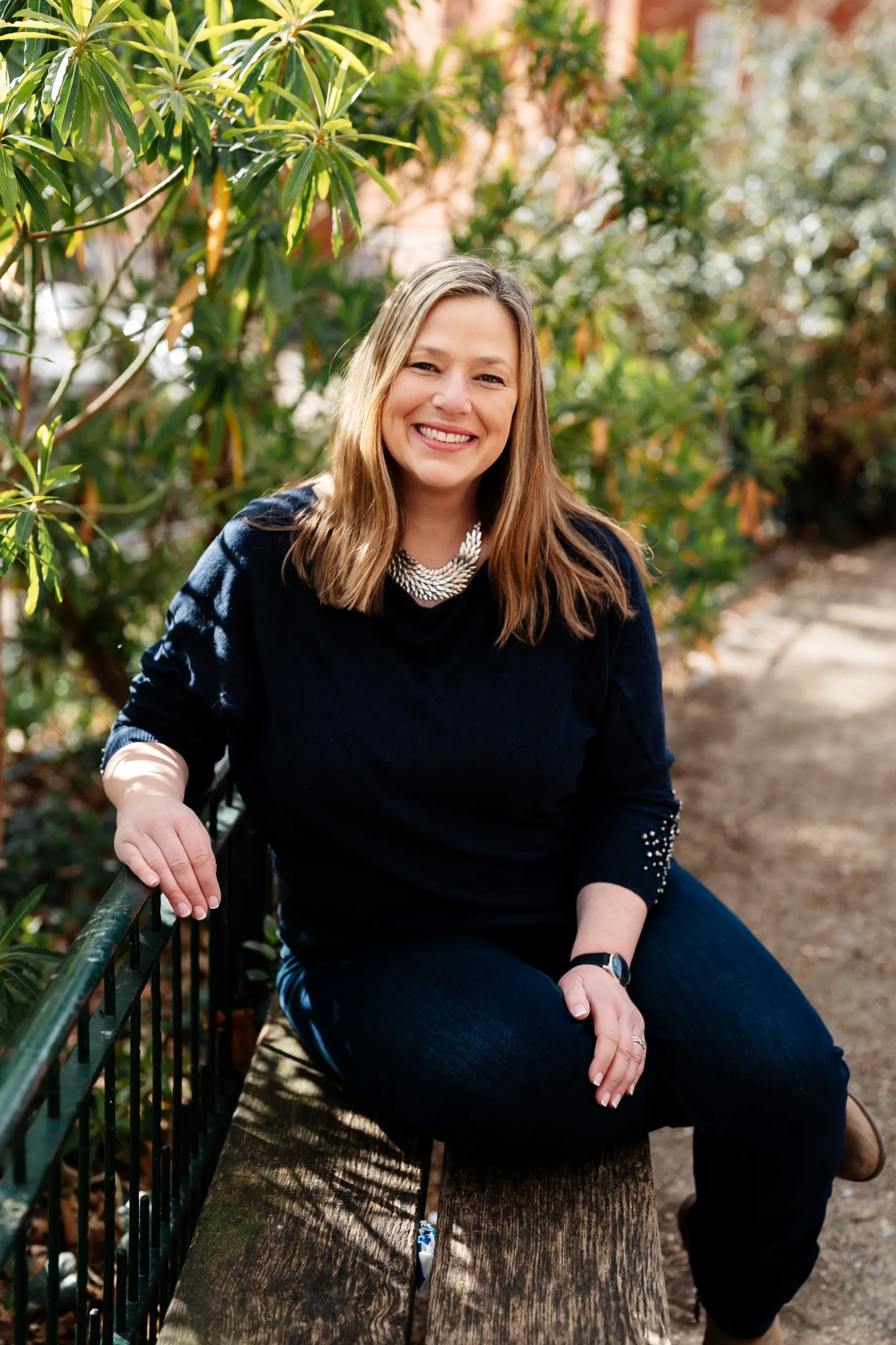 Dressed in black, female founder of Creative Stripes, Lydia Berman, is pictured outside her office on a bench surrounded by vibrant plant life