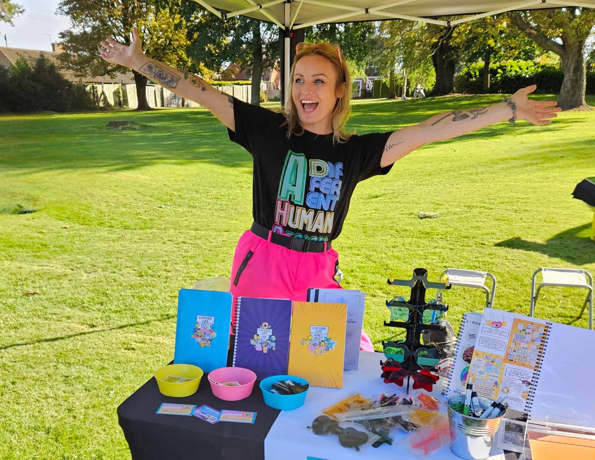 Wellbeing practitioner Lindzi sharing ADHD tools and journals at an outdoor festival